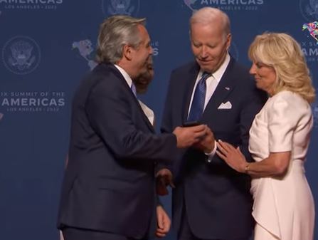 Fernández le muestra a Biden su hijo en el celular.